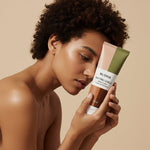 Woman with natural curly hair holding RUTAM 360° PRO SHIELD – exosome scalp treatment for natural and coily hair types, 100ml cream-gel formula
