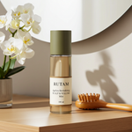 RUTAM Ageless Revitalizing Scalp & Volume Mist 100ml on wooden bathroom shelf with white orchids and scalp massage brush – daily scalp mist for hair shedding and volume support